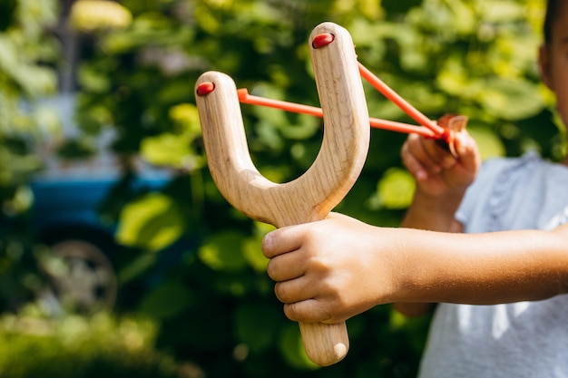 Close up wooden slingshot toy in hands of little girl