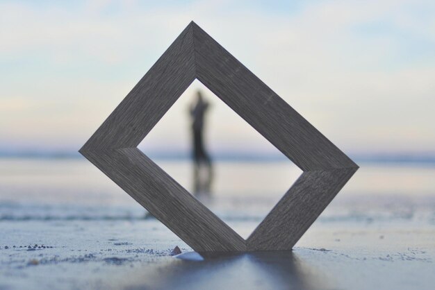 Photo close-up of wooden table by sea against sky