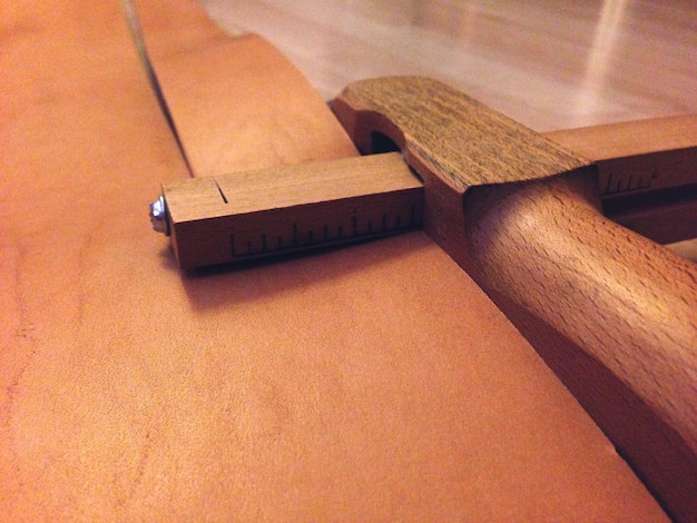 Клоуз-ап деревянного рабочего инструмента для резки кожи для изготовления пояса в мастерской.