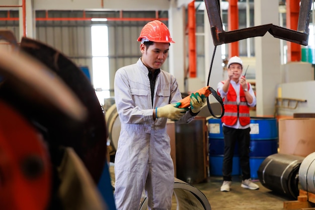 Close up worker hands control indoor overhead crane to lift up metal construction object on metal sheet factory