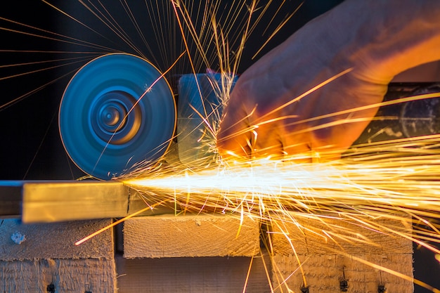 Close-up of worker hands cutting metal with grinder.