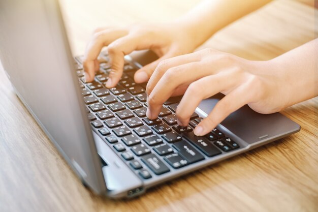 Photo close up of a worker typing a laptop computer