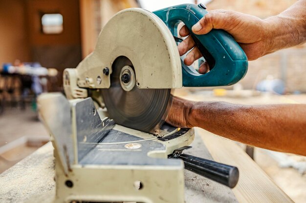 Foto piano ravvicinato di un lavoratore che gestisce con le mani una macchina da taglio sul cantiere