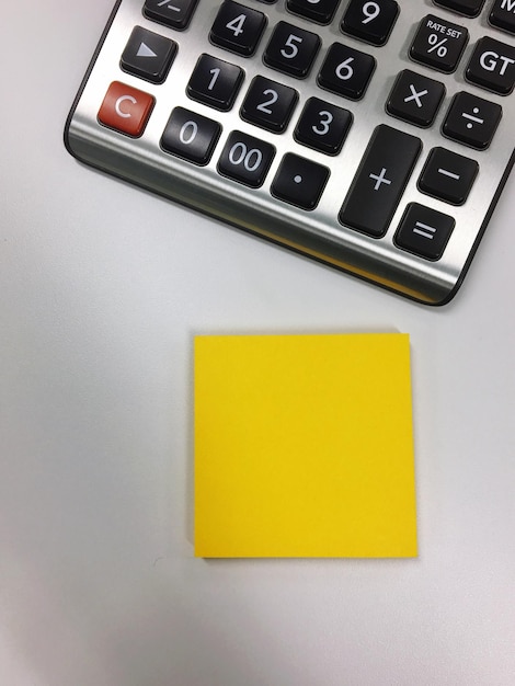 Close-up of yellow adhesive note by calculator