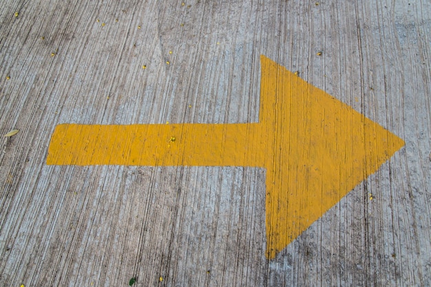 Photo close-up of yellow arrow symbol on wood