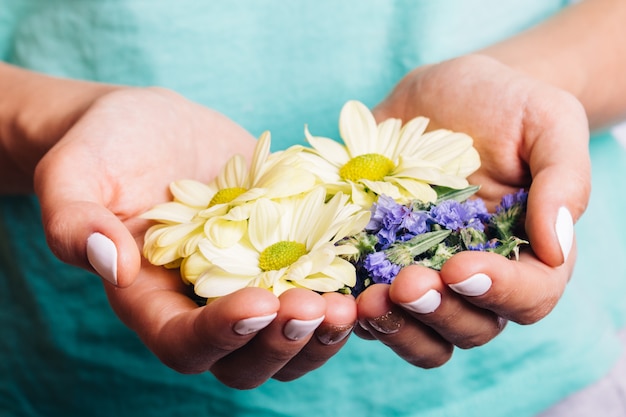 開いている女性の手のひらに黄色と青の花のクローズアップ