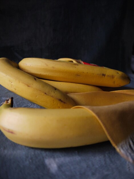 Foto close-up di un grappolo giallo di banane su un tavolo con velluto grigio blu e silk giallo