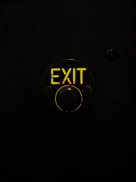 Photo close-up of yellow exit sign against black background