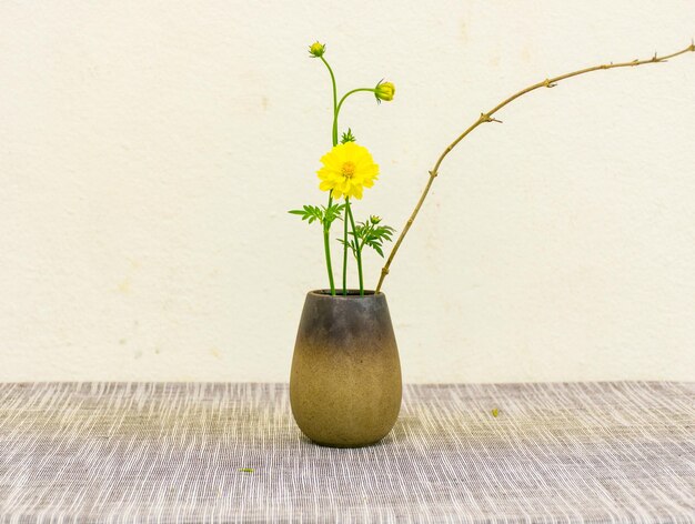 Close-up of yellow flower vase on table against wall