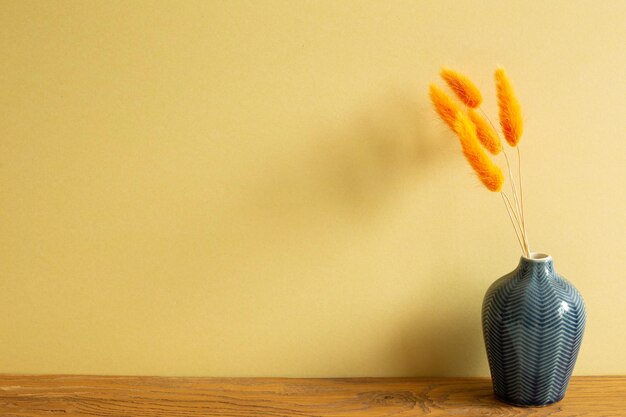 Close-up of yellow flower vase on table against wall