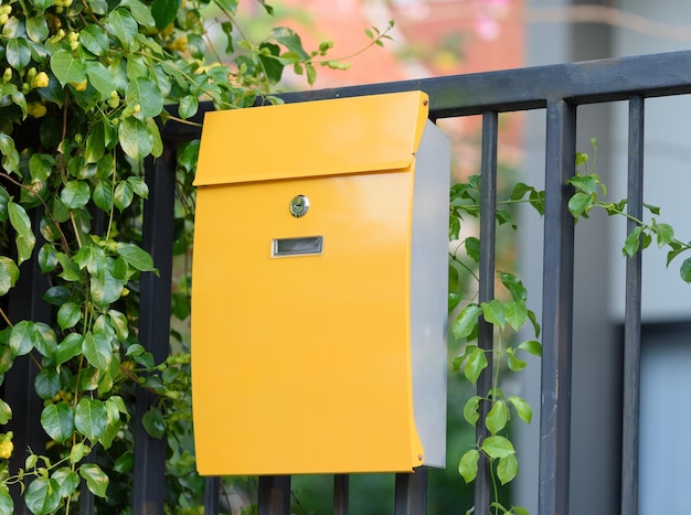 Photo close-up of yellow mailbox on fence