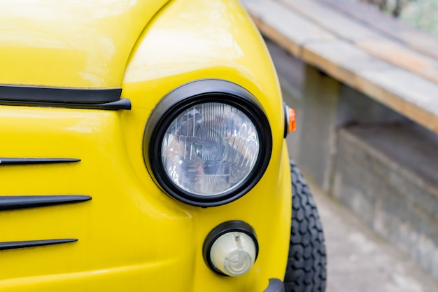 Close up of yellow retro car with round headlights