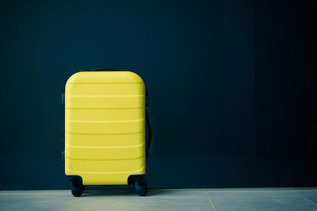 Close-up of yellow trolley bag against blue wall indoors