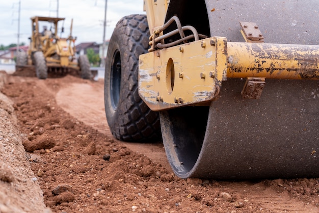 Close up Yellow vibratory soil and Motor Grader Civil compactor working on road construction site