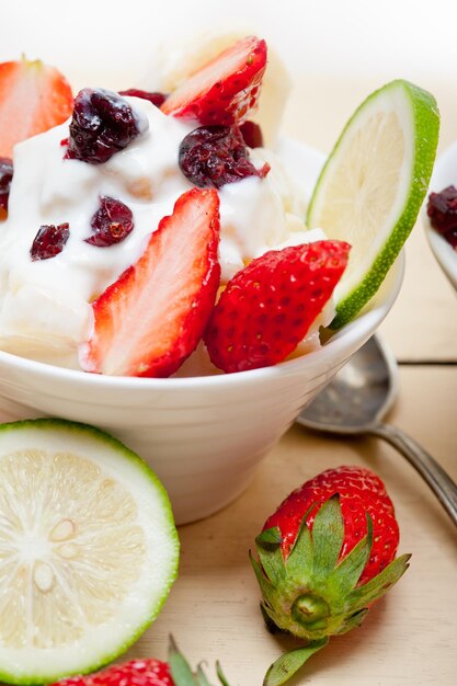 Photo close-up of yogurt with fruits in container on table