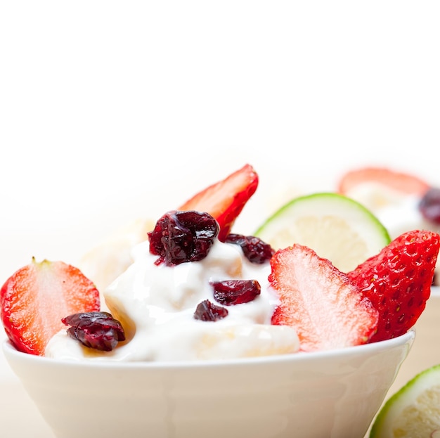 Close-up of yogurt with strawberries in bowl against white background