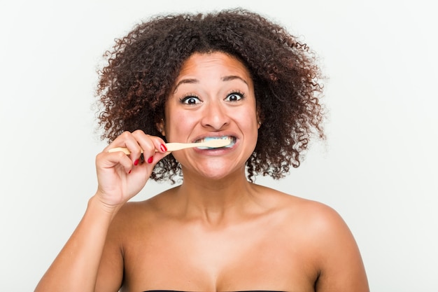 Primo piano di una giovane donna afro-americana lavarsi i denti con uno spazzolino da denti