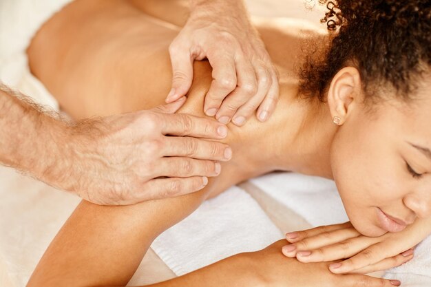 Close up of young african american woman enjoying massage in relaxing spa session and smiling