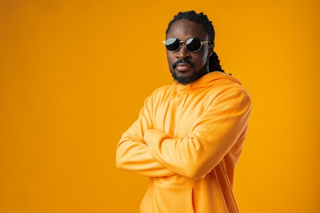 Close up of young african man in sunglasses standing against yellow background