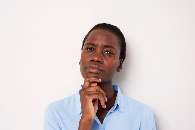 Close up young african woman thinking with her hand on chin over white background