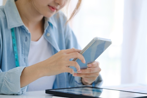 Close up of young asian fashion designer She is using a mobile phone in contact with her customers