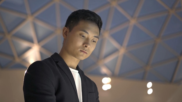 Close up of young asian man in jacket and shirt with interactive wayfinding kiosk