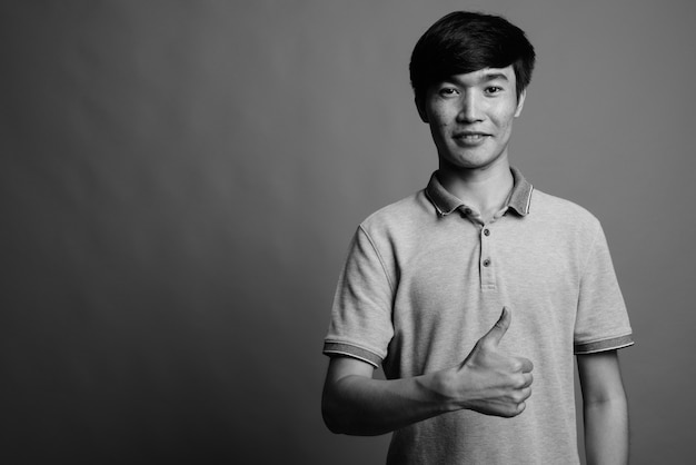 Close up of young Asian man wearing gray polo shirt