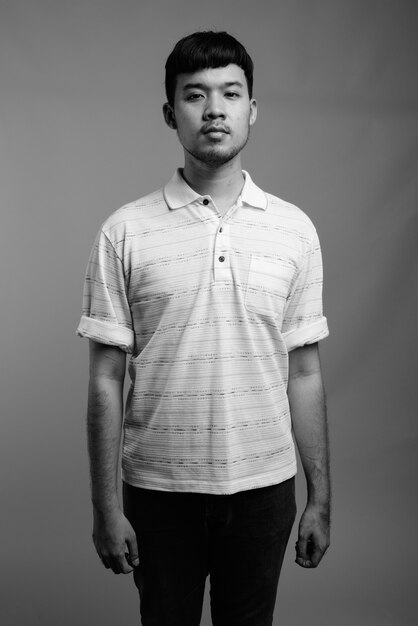 Close up of young Asian man wearing striped polo shirt