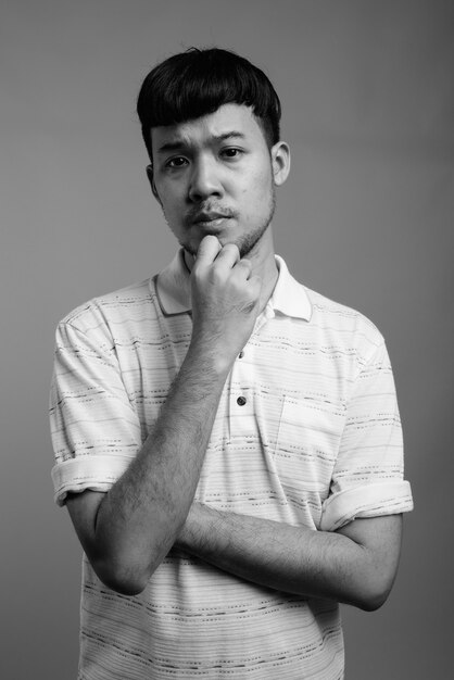 Close up of young Asian man wearing striped polo shirt