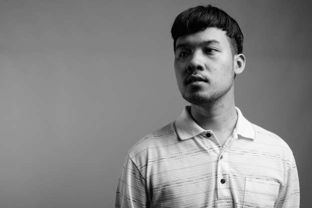 Close up of young Asian man wearing striped polo shirt
