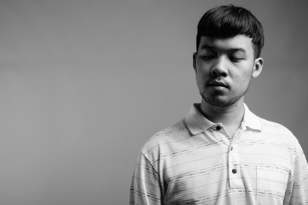 Close up of young Asian man wearing striped polo shirt