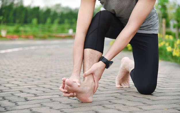 Close up of young asian sports man has pain at muscles and\
joints during outdoor exercise, over trainning or running and sport\
injuty concept