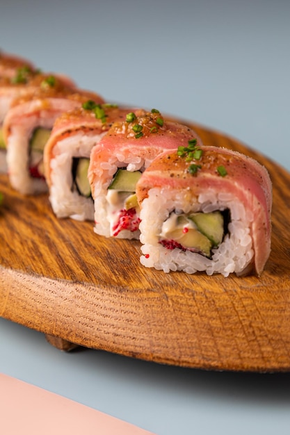 Close up of young Asian woman eating freshly made sushi with salmon shrimps and avocado