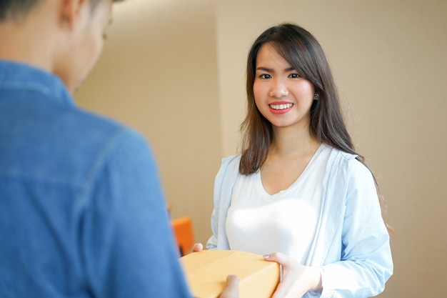 close up on young asian woman receiving tan box from postman 