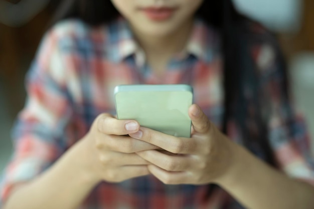 Крупным планом молодая азиатка с помощью мобильного телефона