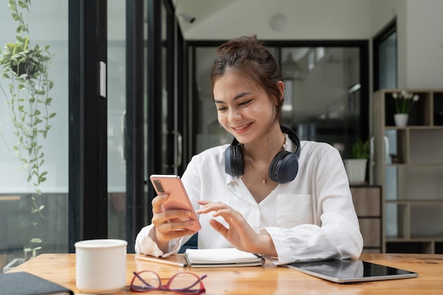 Primo piano di una giovane donna asiatica che utilizza lo smartphone mobile mentre studia online a casa