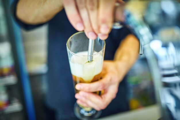 Close-up of young bartender pouring beer while standing at the bar counter.