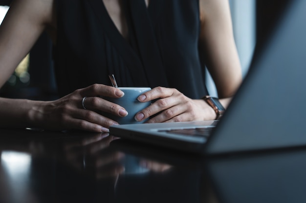 Close up of young beautiful unrecognizable woman hands holding hot cup of coffee or tea.