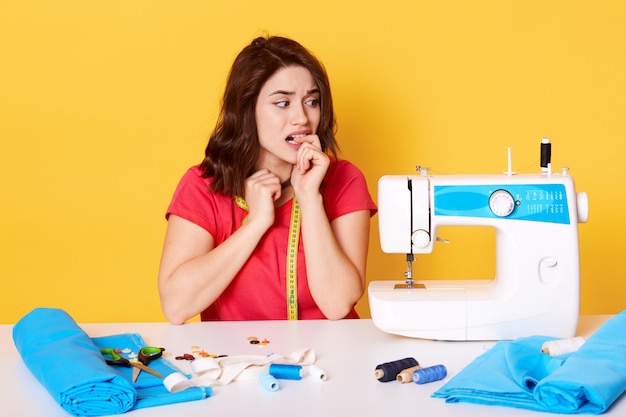 Close up of young bites her nails, has problems with her sewing machine