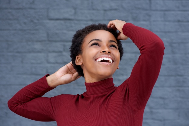 Close up young black woman smiling with hand in hair