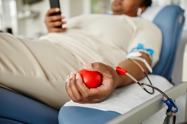 Close up of young black woman squeezing stress ball while giving blood at donation center copy space