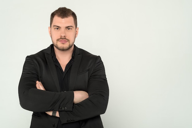 Close up of young business man in a suit with crossed arms on a white background