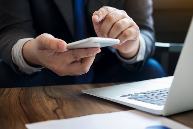 Close up of young business man using mobile smart phone for working in his office.