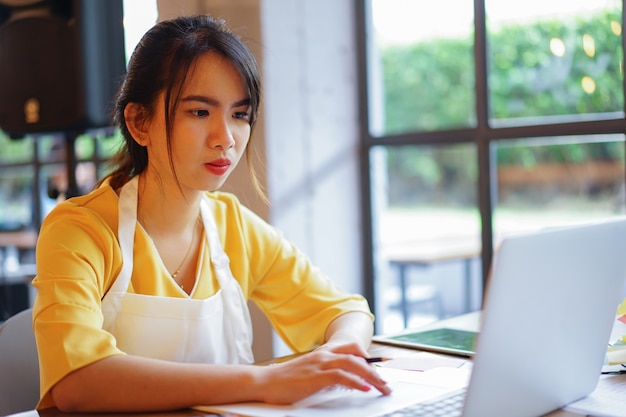 노트북을 사용하는 젊은 사업 소유자 아시아 여자를 닫습니다