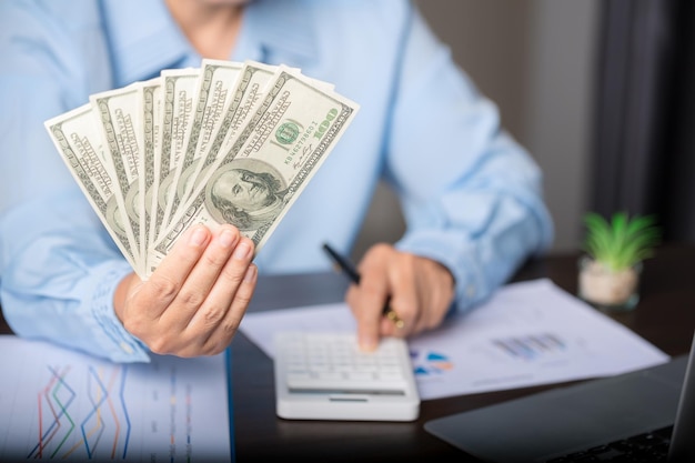 Close up young business woman using counting cash money one hundred dollar bills checking financial documents