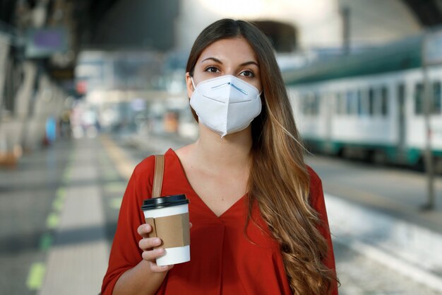 Close up of young businesswoman with face mask waiting for train to go to work