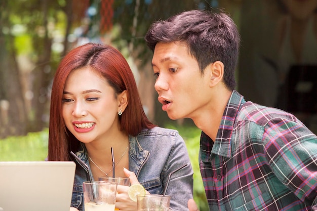 Close up of young couple using laptop in cafe