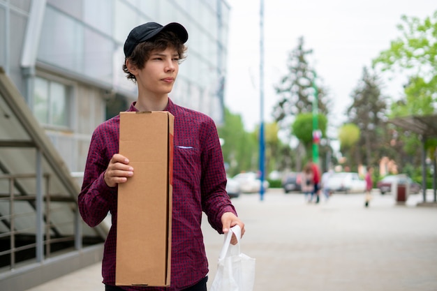 Close up young courier waiting for a client customers in the city