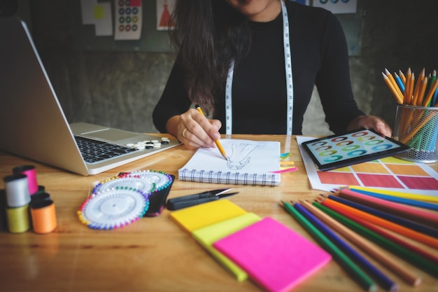 Close-up of young creative fashion designer working hard on project at a modern home office