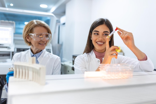 Close up of young doctor in biochemistry analysing and holding test tube with sample of genetic material Chemistry researcher in sterile laboratory using modern technology to test microbiology liquid